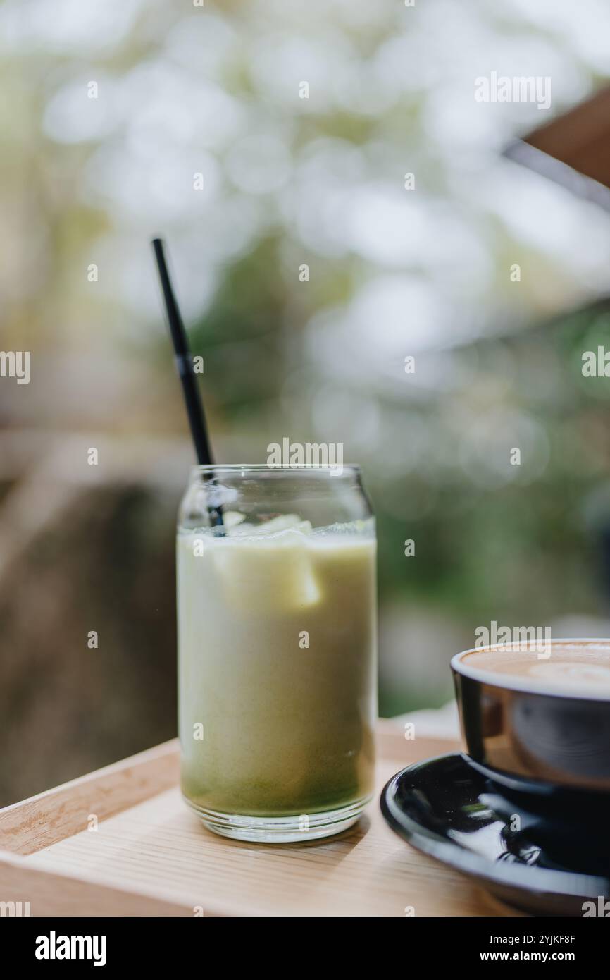 Japanischer Eismatcha Latte, grüner Tee mit Milch, Sojamilch, mit Strohhalm im Glas. Café im Freien Stockfoto