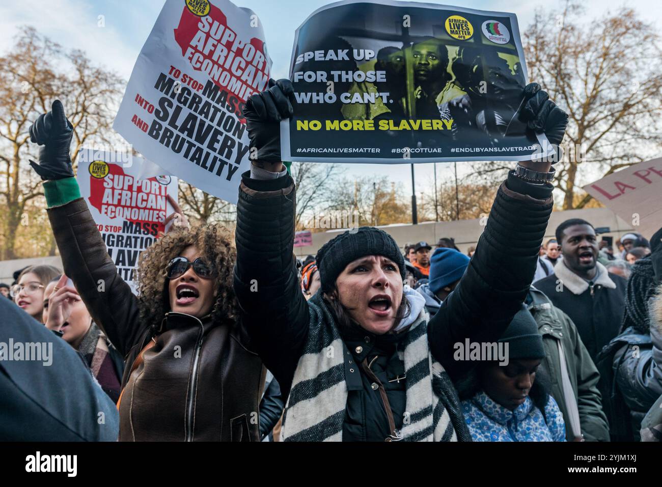 London, Großbritannien. Dezember 2017. Ein Mann in weißen Gewändern beendet eine afrikanische Trankationszeremonie zu Ehren der Helden afrikanischer Kämpfe, indem er die Menge beim Protest vor der libyschen Botschaft gegen den Verkauf von Schwarzen Afrikanern durch arabische Sklavenhändler in Libyen mit Wasser übergießt. Der von African Lives Matter veranstaltete marsch erforderte die Schließung der libyschen Haftanstalten, Maßnahmen afrikanischer Regierungen zur Rettung der in den Lagern inhaftierten Menschen sowie die Verurteilung des Sklavenhandels und der Morde an Migranten durch alle afrikanischen Führer und die Vereinten Nationen und forderte Libyen auf, Gesetze zu erlassen und durchzusetzen, die diese Verbrechen verhindern Stockfoto