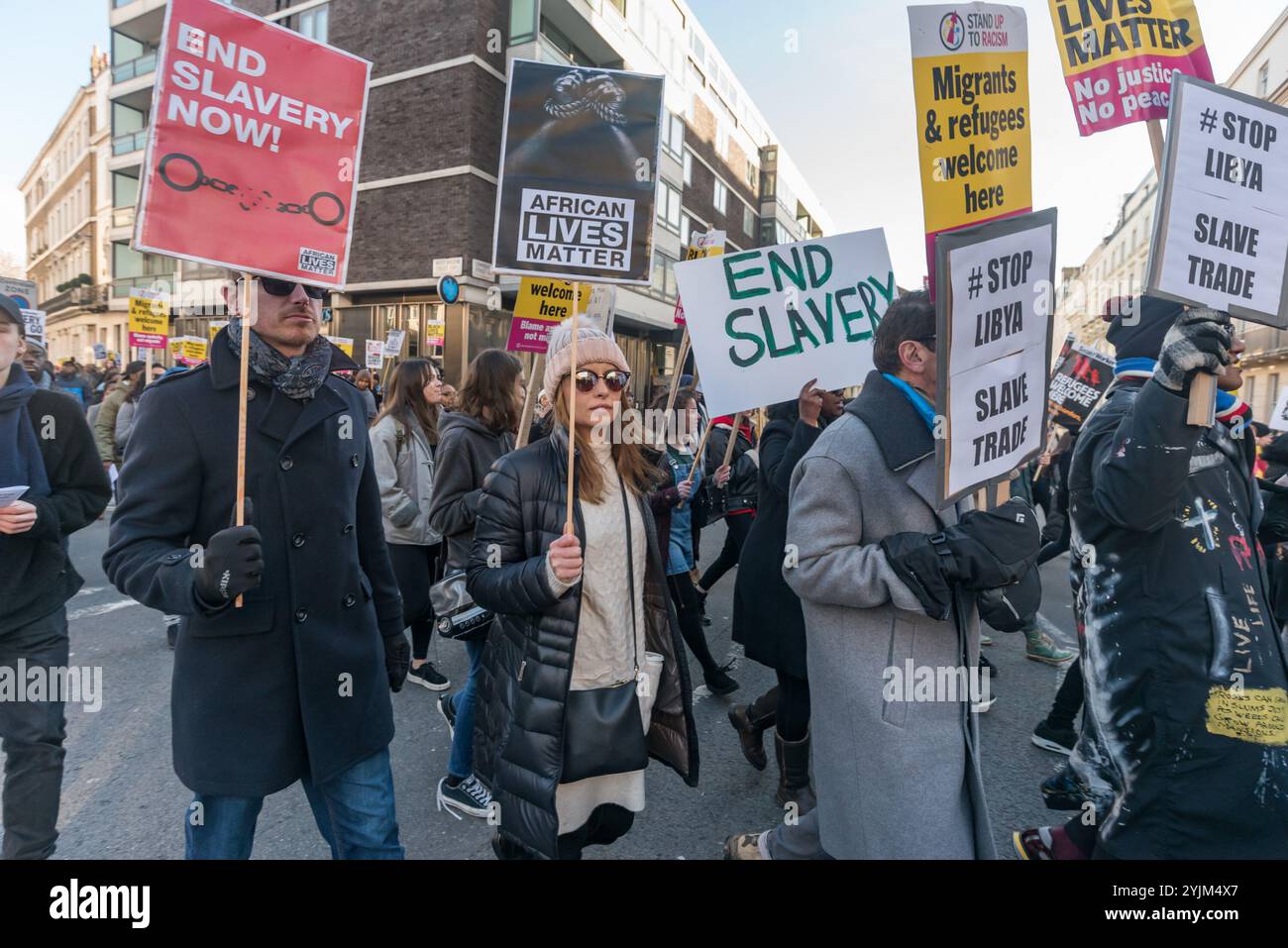 London, Großbritannien. Dezember 2017. Ein Mann in weißen Gewändern beendet eine afrikanische Trankationszeremonie zu Ehren der Helden afrikanischer Kämpfe, indem er die Menge beim Protest vor der libyschen Botschaft gegen den Verkauf von Schwarzen Afrikanern durch arabische Sklavenhändler in Libyen mit Wasser übergießt. Der von African Lives Matter veranstaltete marsch erforderte die Schließung der libyschen Haftanstalten, Maßnahmen afrikanischer Regierungen zur Rettung der in den Lagern inhaftierten Menschen sowie die Verurteilung des Sklavenhandels und der Morde an Migranten durch alle afrikanischen Führer und die Vereinten Nationen und forderte Libyen auf, Gesetze zu erlassen und durchzusetzen, die diese Verbrechen verhindern Stockfoto