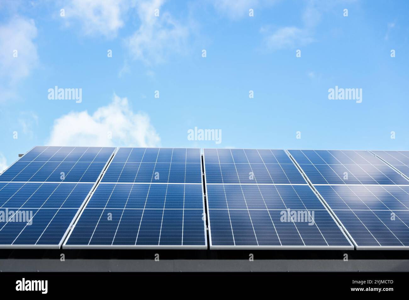 Solarzellen auf wolkenblauem Himmel Hintergrund. Sauberes Konzept für alternative Energie. Modernes Haus mit Solarpaneelen, eigenständige Photovoltaikanlage Stockfoto