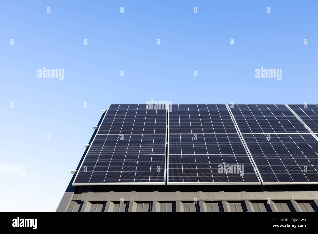 Modernes Haus mit Solarpaneelen eigenständiges Photovoltaik-Anlagensystem auf Haushaltsblech Dach. Blauer Hintergrund. Sauberes Alternativerg Stockfoto