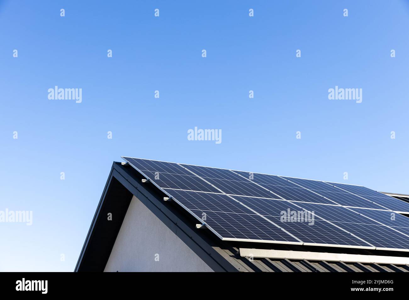 Modernes Haus mit Solarpaneelen, eigenständiges Photovoltaik-Anlagensystem auf dem Dach des Haushaltsblechs. Blauer Hintergrund. Saubere Alternative en Stockfoto