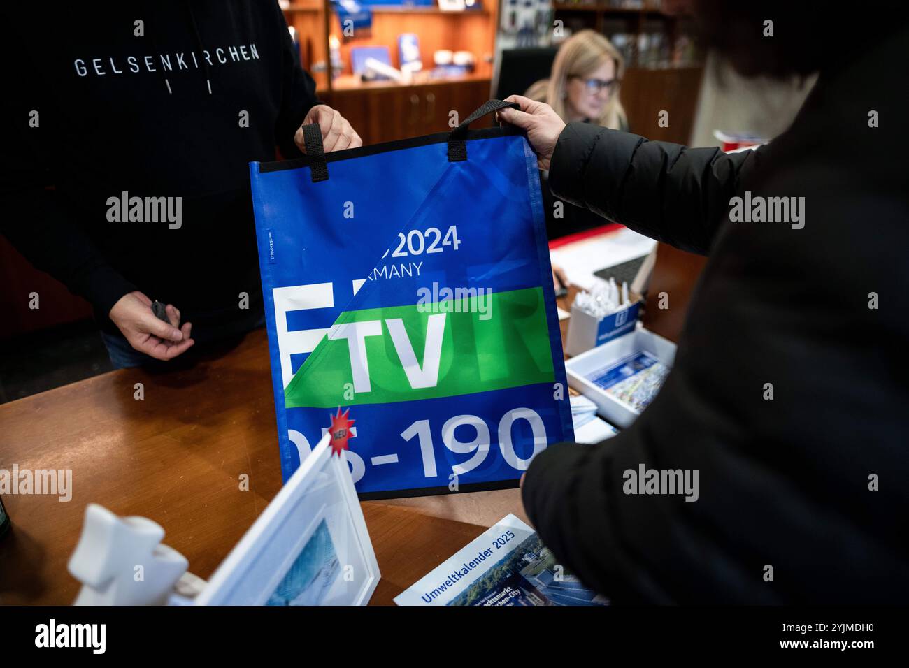 Gelsenkirchen, Deutschland. November 2024. Einem Kunden wird eine Tasche gezeigt. Produkte aus Fahnen, Lätzchen und Fahnen der Europameisterschaft werden nun gut vier Monate nach der Fußball-Europameisterschaft verkauft. Das Projekt wird von der Stadt und den Kooperationspartnern vorgestellt. Der Erlös fließt für einen guten Zweck. Quelle: Fabian Strauch/dpa/Alamy Live News Stockfoto