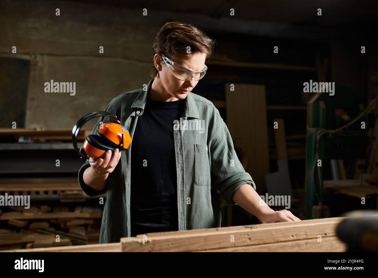 Die Schreinerin konzentriert sich intensiv auf das Formen von Holz, umgeben von Werkzeugen und Holz in ihrer Werkstatt. Stockfoto