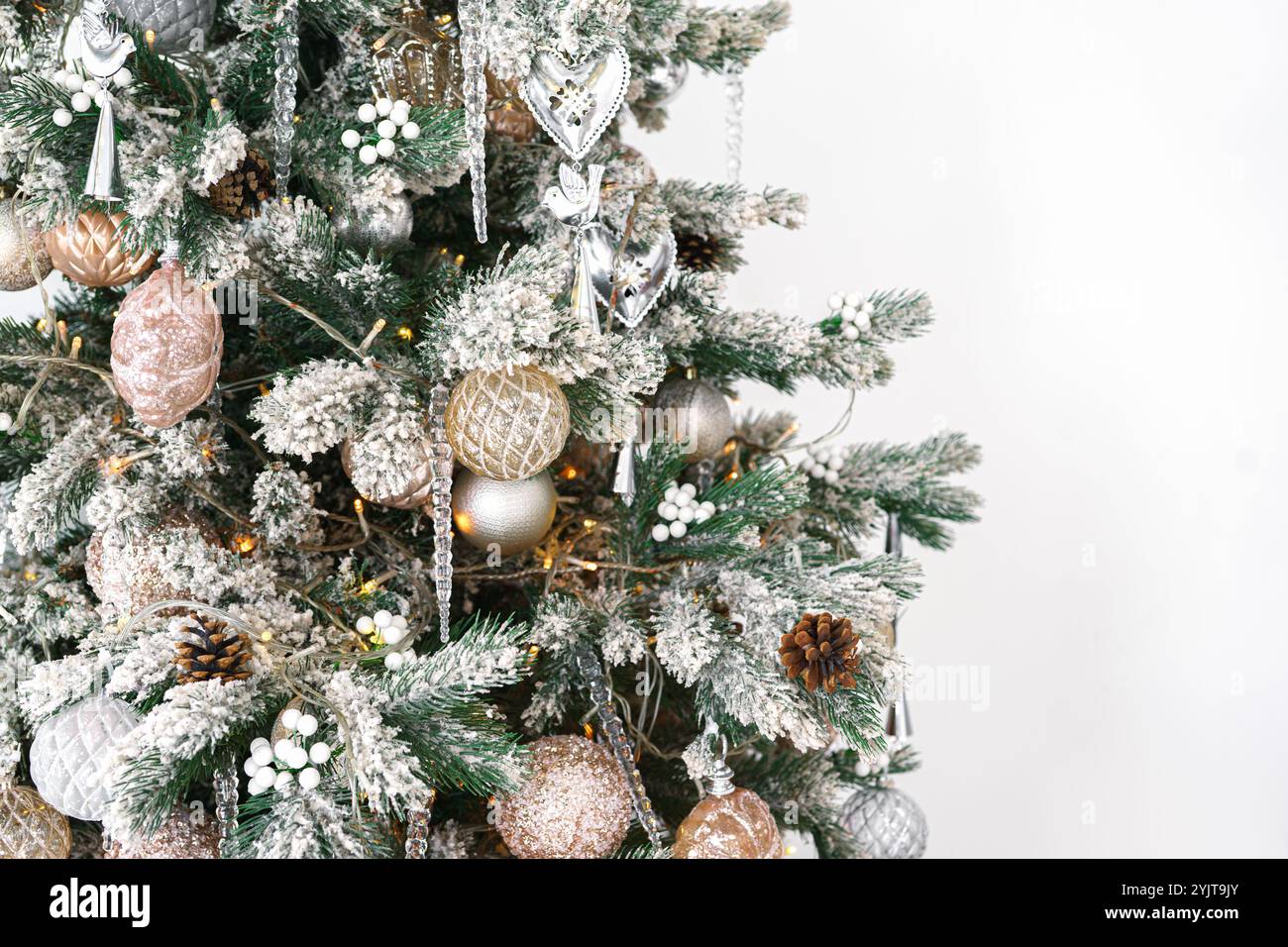 Geschmückter Weihnachtsbaum mit mattierten Zweigen, glitzernden Ornamenten und leuchtenden Lichtern isoliert auf weißem Hintergrund. Festliche Atmosphäre für Urlaub c Stockfoto