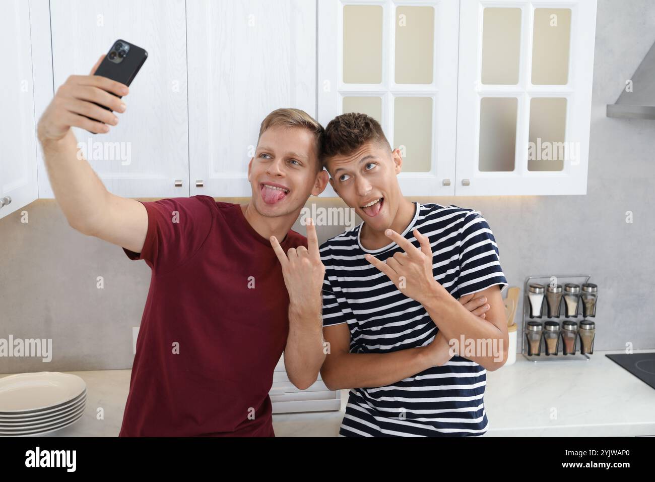 Junge Brüder machen Selfie und zeigen Gesten in der Küche Stockfoto
