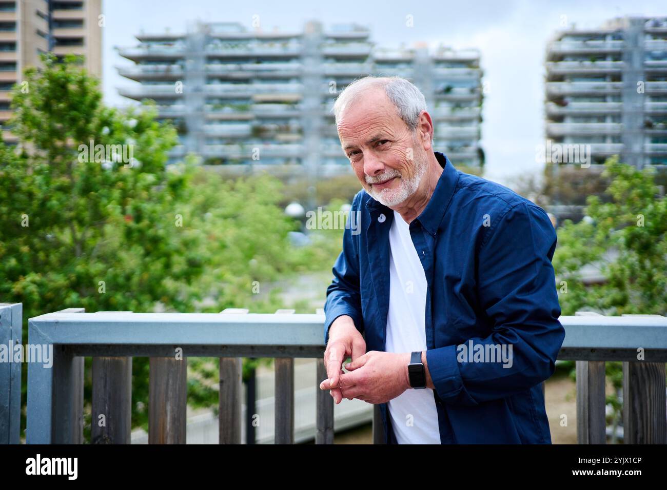 Porträt eines gutaussehenden kaukasischen reifen Mannes, der sich auf einer Schiene vor dem Garten im Pflegeheim posiert. Stockfoto