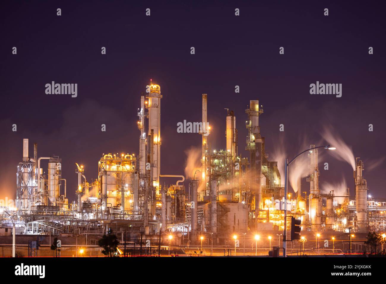 Nächtliche Ansicht einer Raffinerie, die giftige CO2-Treibhausgase ausspuckt, die die globale Erwärmung verursachen. Stockfoto
