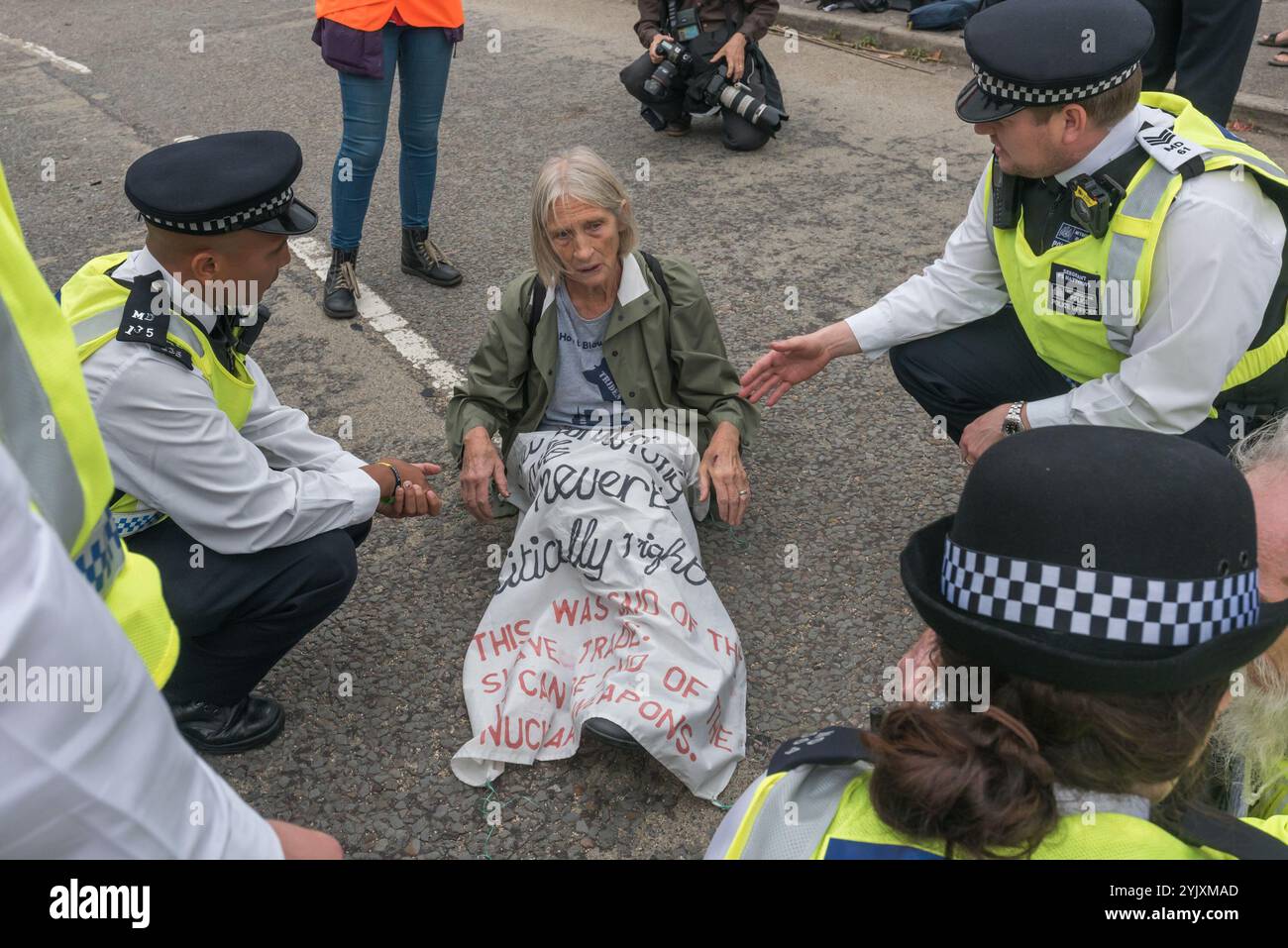 London, Großbritannien. 5. September 2017.die Polizei spricht mit einem Quäker-Demonstranten, der am zweiten Tag der Proteste gegen die weltweit größte Waffenmesse in den Londoner docklands auf der Straße saß. Der „No Faith in war“-Tag war eine Reihe von Veranstaltungen, die von verschiedenen Glaubensgruppen organisiert wurden. Bevor ich ankam, gab es eine Sperre auf der Zufahrtsstraße, die die Lieferungen stoppte, um die Messe durch das Osttor zu errichten. Es folgte ein Quäker-Treffen am Straßenrand, bei dem eine Reihe von Personen standen oder saßen, um die Straße zu blockieren, und mehrere, die sich weigerten, sich zu bewegen, wurden verhaftet. Dann kamen vier Demonstranten herab Stockfoto