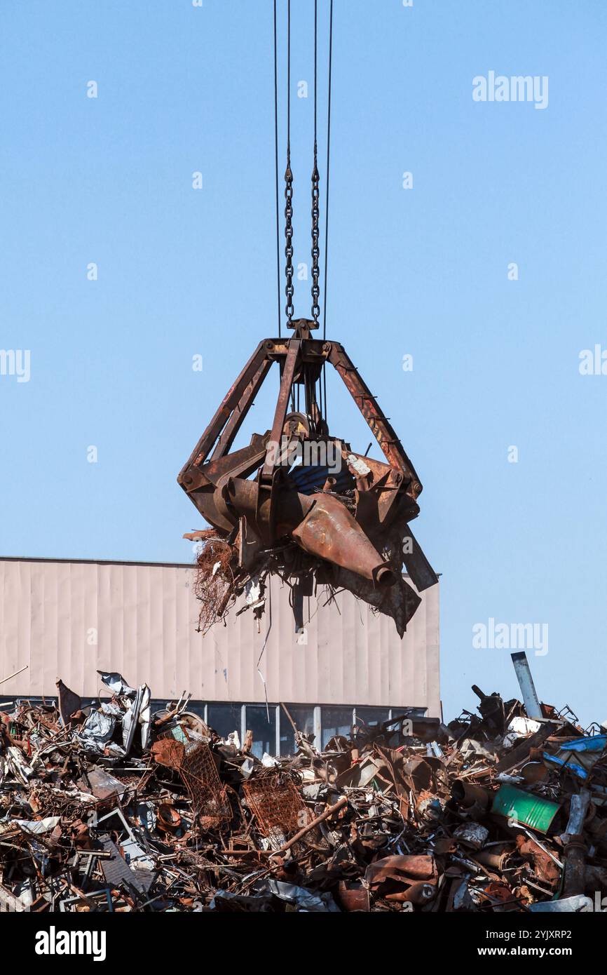 Hydraulischer Greifer zum Anheben von rostigem Metallschrott zum Recycling, vertikales Foto Stockfoto