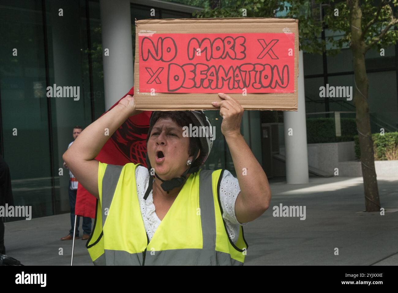 London, Großbritannien. Juli 2017. Eine Frau hält ein Poster „No More Defamation“ auf dem Protest der Cleaners and Allied Independent Workers Union (CAIWU) vor den Büros von Facebook in London gegen das „hässliche Gesicht von Facebook“ hoch, in dem sie fordert, dass die Putzer dort das Londoner Lebenshaltungslohn erhalten und dass der Manager vor Ort Anschuldigungen von Rassismus, Mobbing und Vetternwirtschaft ordnungsgemäß untersucht. Er versuchte, andere Proester und mich zu verraten, bevor er von der Sicherheit weggeführt wurde. In diesen Büros gibt es zwei redundante Verwaltungsebenen: Facebook verwendet weniger Reinigungsmittel als direkt Stockfoto