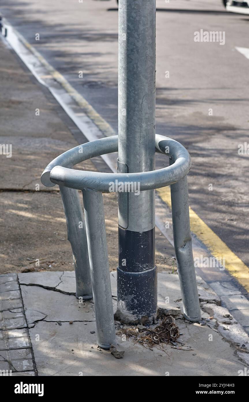 Lichtmast, geschützt durch eine zerknitterte Metallkonstruktion, die Stöße absorbiert. Die Einrichtung zeigt die Wirksamkeit von Sicherheitsmaßnahmen in URBAN en Stockfoto