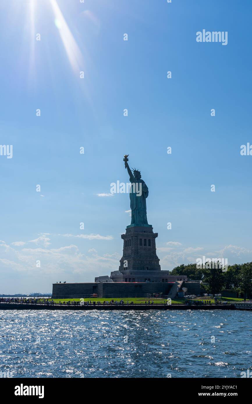 New York City, USA - 20. August 2022: Blick auf Liberty Island und Freiheitsstatue vom Wasser mit Sonnenstrahl, New York City, USA. Stockfoto