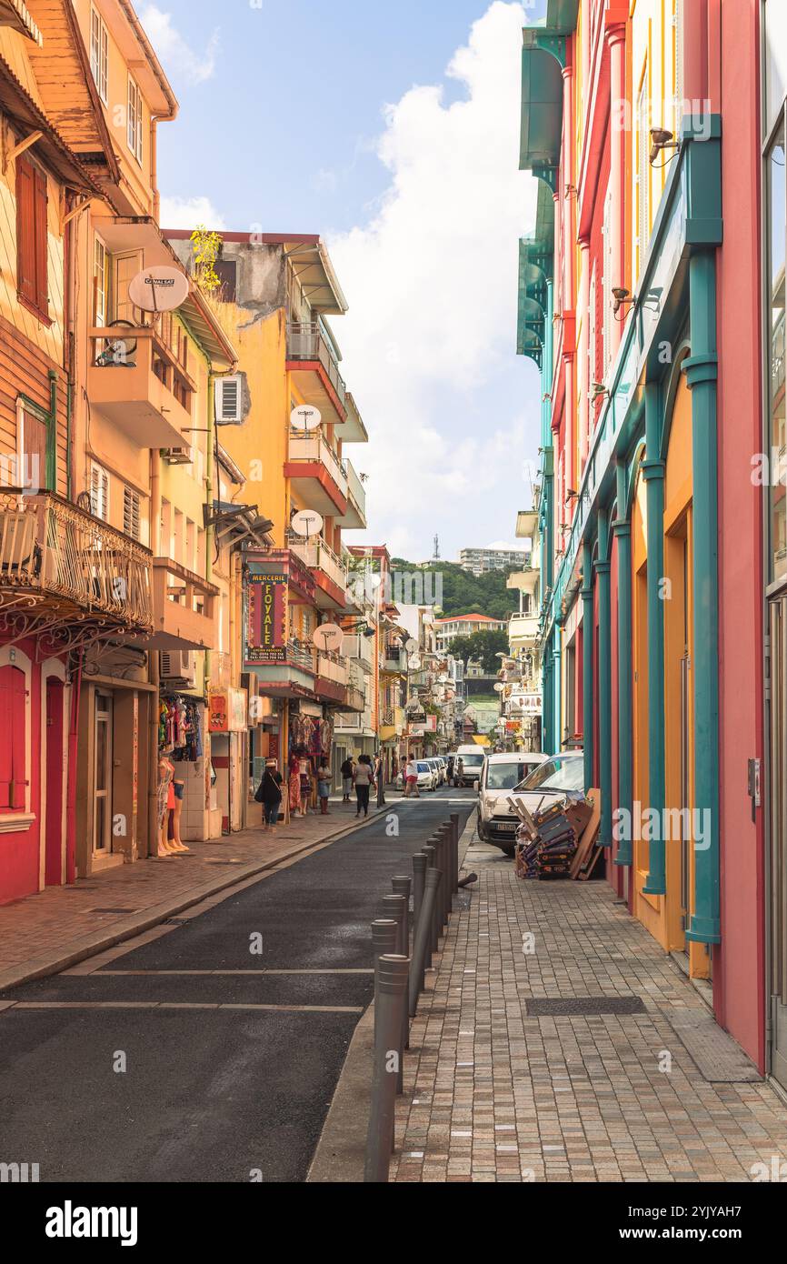 Fort-de-France, Martinique - 3. Januar 2018: Farbenfrohe Gebäude säumen eine lebhafte Straße unter einem klaren, sonnigen Himmel. Stockfoto