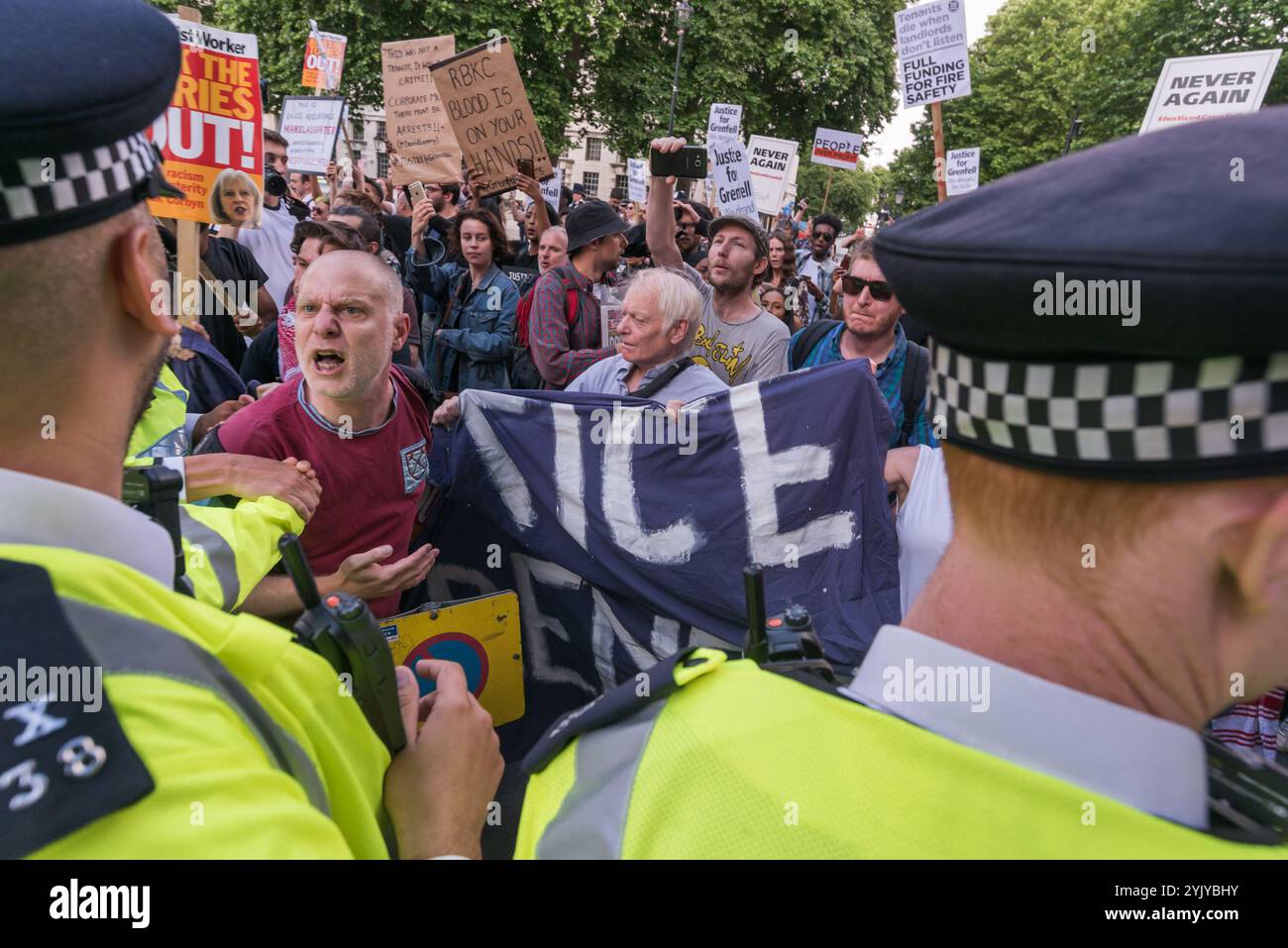 London, Großbritannien. Juni 2017. Die Demonstranten streiten mit der Polizei in der Downing Street und weigerten sich, auf das Pflaster gegenüber zu ziehen, veranstalteten eine laute Kundgebung vor den Toren, bei der Sprecher der North Kensington Community Aktivisten, Bewohner anderer Turmblöcke untergebracht und Rassismus abgelehnt wurden. Sie riefen zum Rücktritt von Theresa May und ihrem Helfer Gavin Barwell auf, der als Wohnungsminister die nach der letzten Londoner Turmblockbrandkatastrophe empfohlenen Änderungen nicht umgesetzt hatte. Nach einer Kundgebung zogen sie dort auf, um zu weiteren Protesten bei der BBC und anderswo zu marschieren. Stockfoto