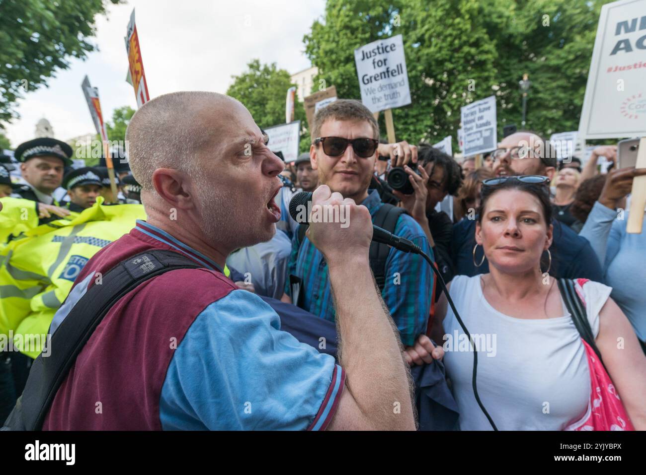 London, Großbritannien. Juni 2017. Michael Bradley spricht vor der Downing Street, wo Demonstranten, die sich weigerten, auf den Pflaster gegenüber zu ziehen, eine laute Kundgebung vor den Toren veranstalteten, bei der Sprecher der North Kensington Community Aktivisten, Bewohner anderer Turmblöcke untergebracht und Rassismus verteidigt wurden. Sie riefen zum Rücktritt von Theresa May und ihrem Helfer Gavin Barwell auf, der als Wohnungsminister die nach der letzten Londoner Turmblockbrandkatastrophe empfohlenen Änderungen nicht umgesetzt hatte. Nach einer Kundgebung zogen sie dort auf, um zu weiteren Protesten bei der BBC und anderswo zu marschieren. Stockfoto