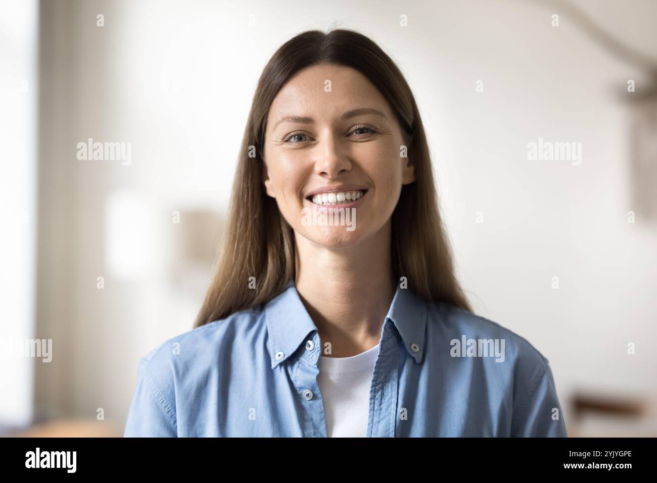 Hübsche Frau in lässigem Denim-Hemd, die in die Kamera schaut Stockfoto