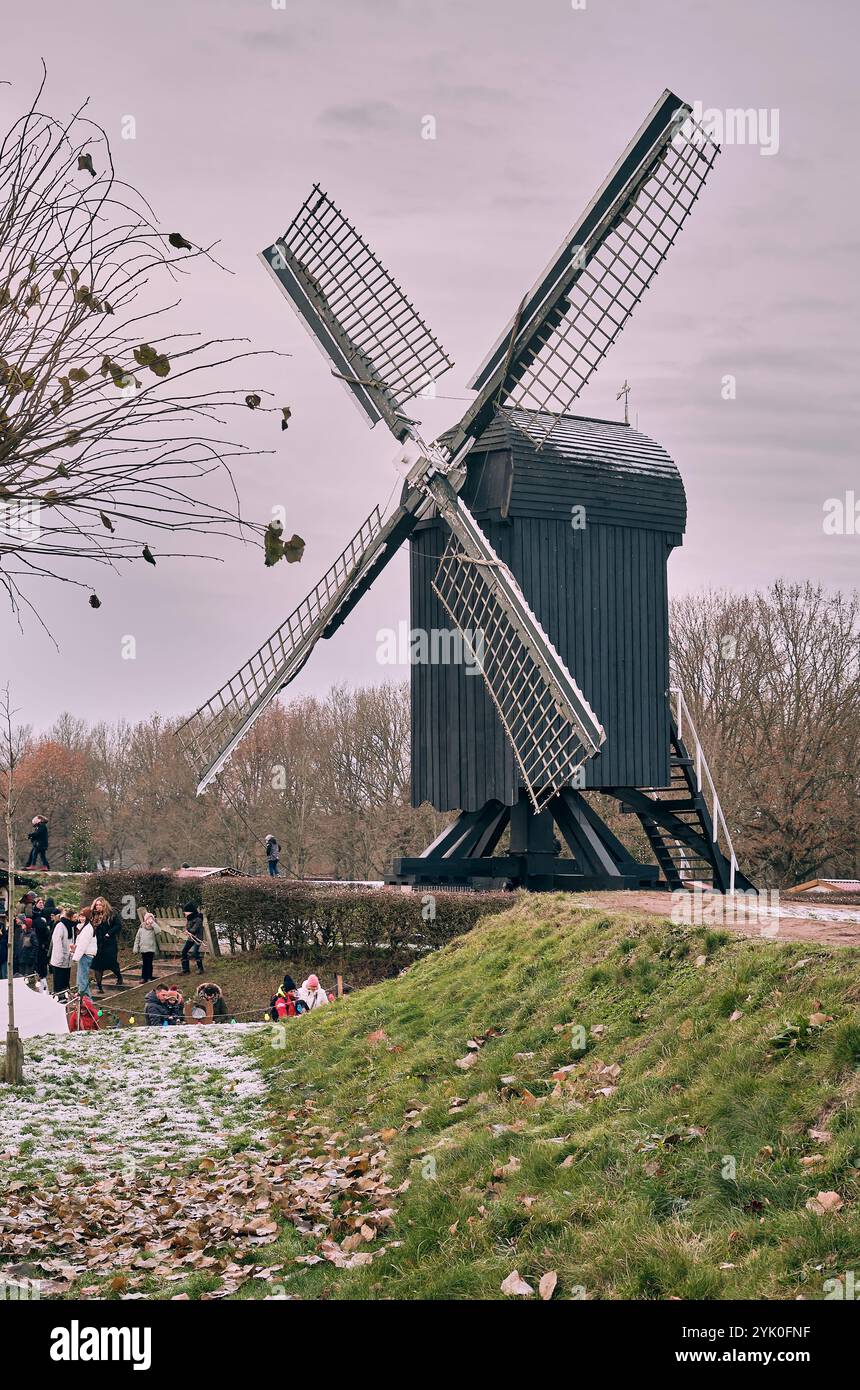 Ein Winterblick auf die historische nachgebildete Windmühle auf dem Burggraben Bourtange mit Lichtern und vorbeischlendernden Besuchern des Weihnachtsmarktes. Stockfoto