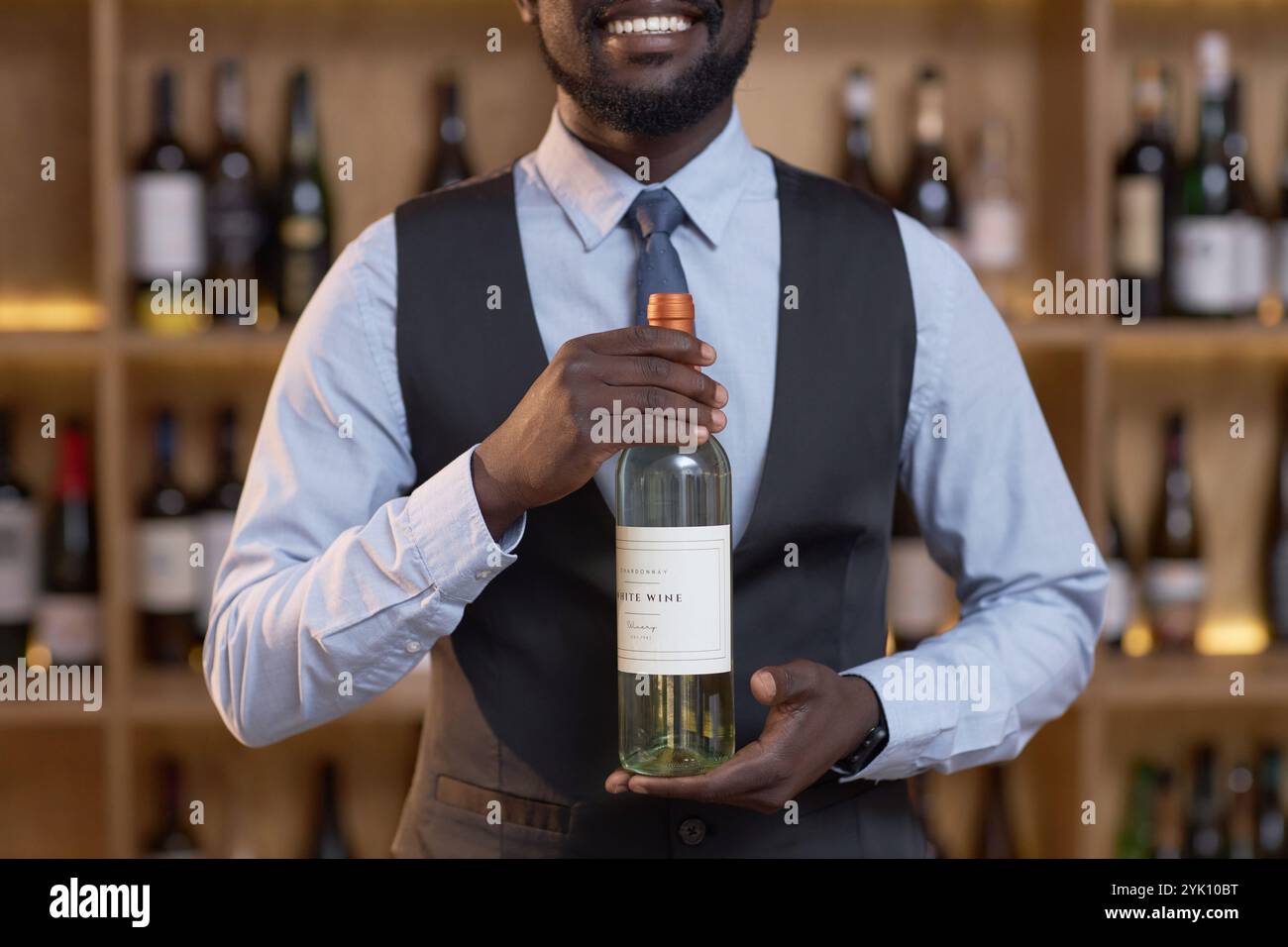 Mittlere Nahaufnahme eines nicht erkennbaren afroamerikanischen Sommeliers, der teure Flasche Reifen Wein hält Stockfoto