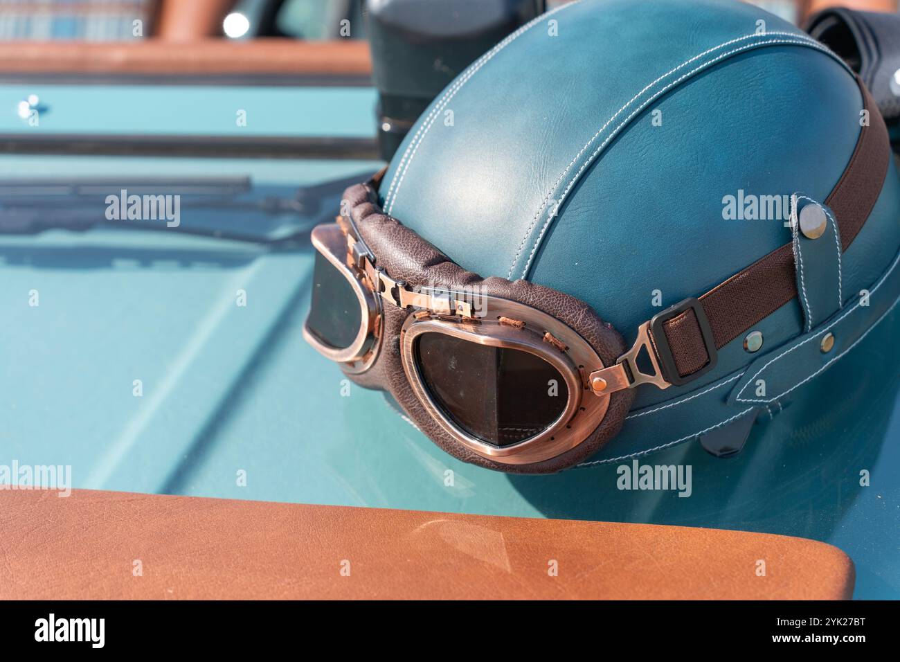 Blaugrüner Oldtimer-Helm und Brille an einem alten Auto Stockfoto