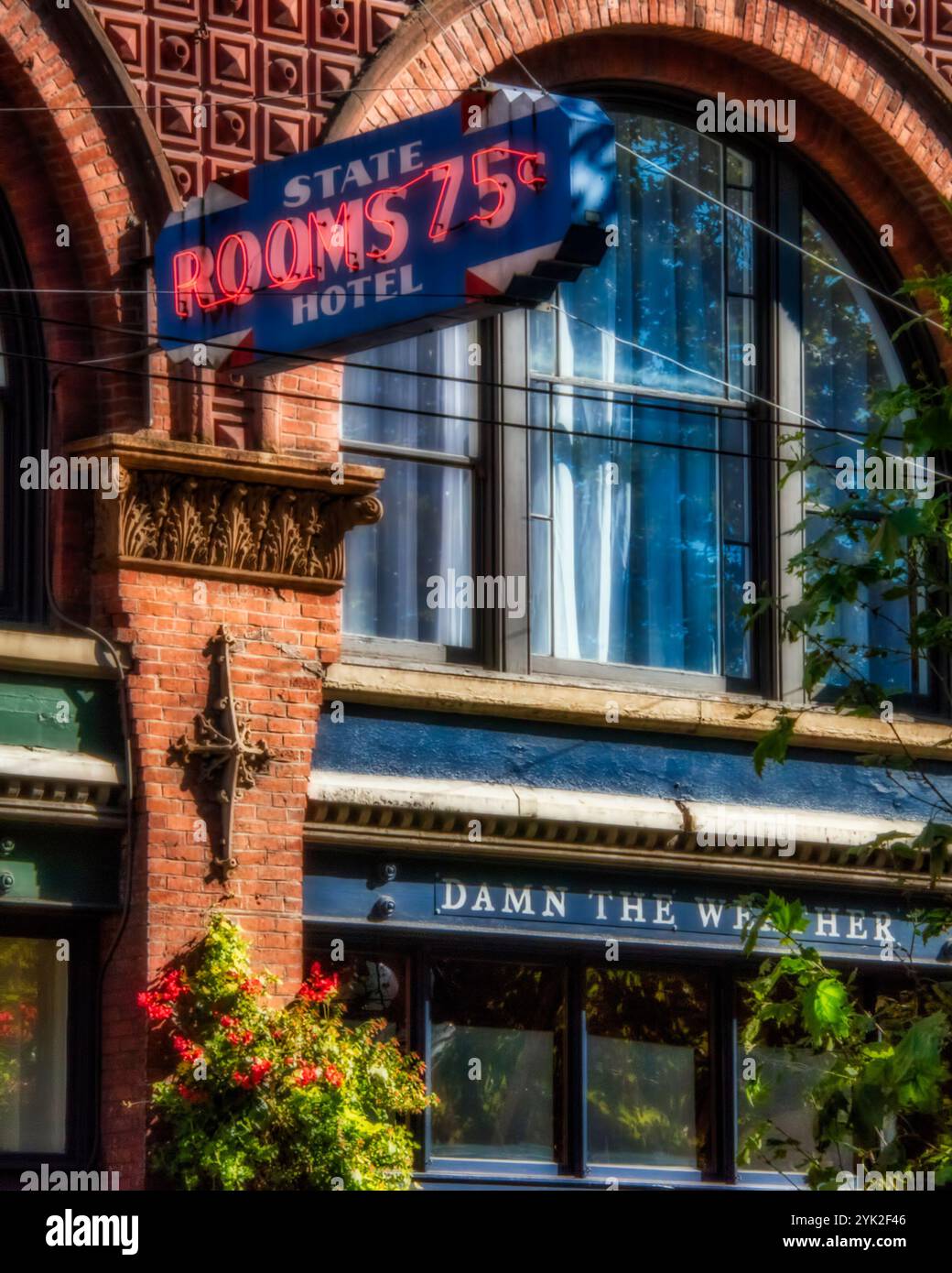 "Verdammt das Wetter“ – ein farbenfrohes Stück altes Seattle im historischen Pioneer Square, wo kunstvolle Ziegelverkleidung, gewölbte Fenster und ein wunderbar respektloser s Stockfoto