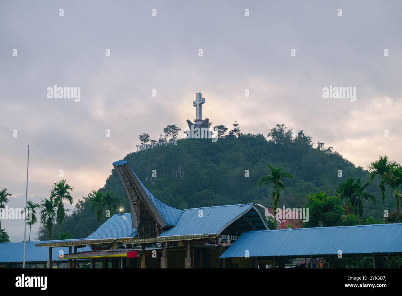 Ein großes Kreuz auf einem Berg mit einem traditionellen Toraja-Haus und den Worten Nord-Toraja Stockfoto