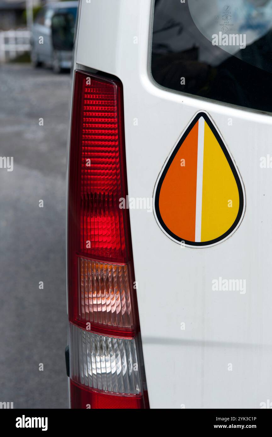 Ein orangefarbener und gelber Warnhinweis-Aufkleber auf der Rückseite eines japanischen Autos ist ein Symbol für einen älteren Fahrer. Stockfoto