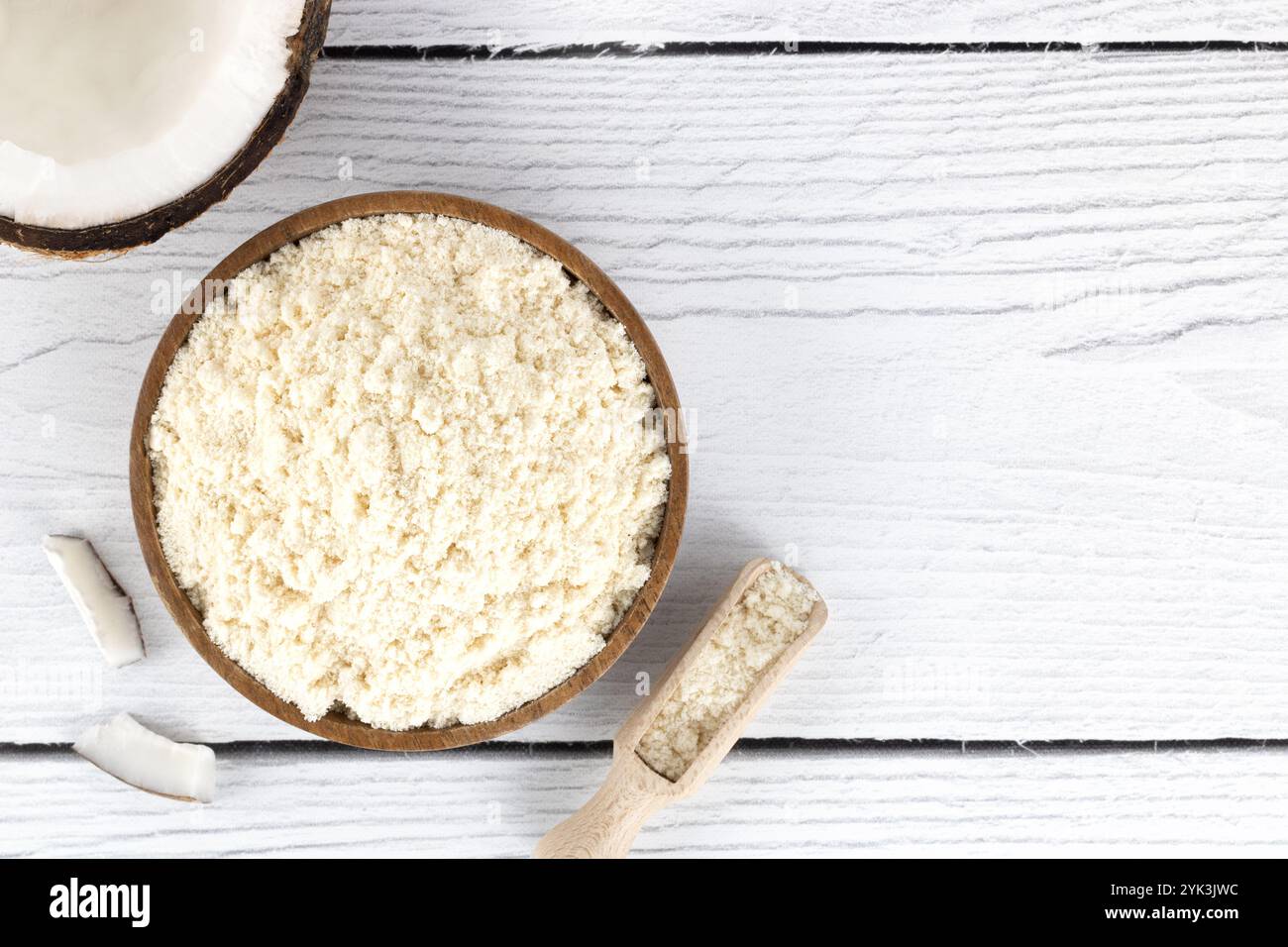 Kokosmehl in einer Holzschüssel und frische Kokosnüsse auf weißem hölzernem Hintergrund. Backzutaten. Glutenfreie Speisen Stockfoto