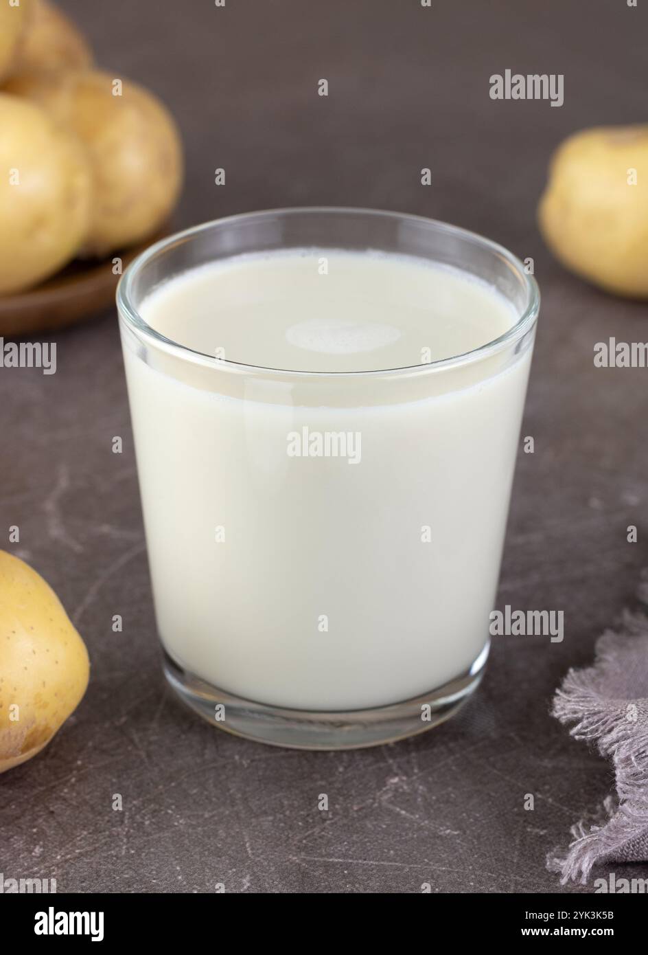Vegane Kartoffelmilch und Kartoffeln auf braunem Hintergrund. Pflanzliche laktosefreie Milch. Gemüsemilch. Stockfoto