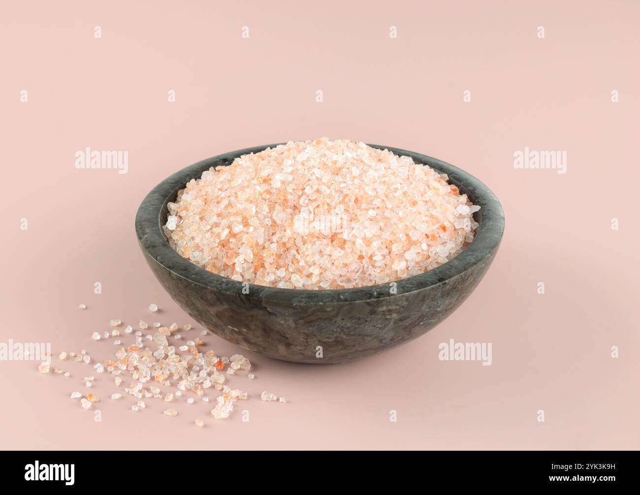 Himalaya kristallines rosafarbenes Salz in einer grauen Schüssel auf rosa Hintergrund. Gewürze Hintergrund. Stockfoto