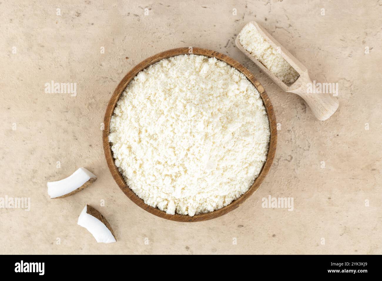 Kokosmehl in einer Holzschale auf beigefarbenem Hintergrund. Draufsicht. Backzutaten. Glutenfreie Speisen. Stockfoto