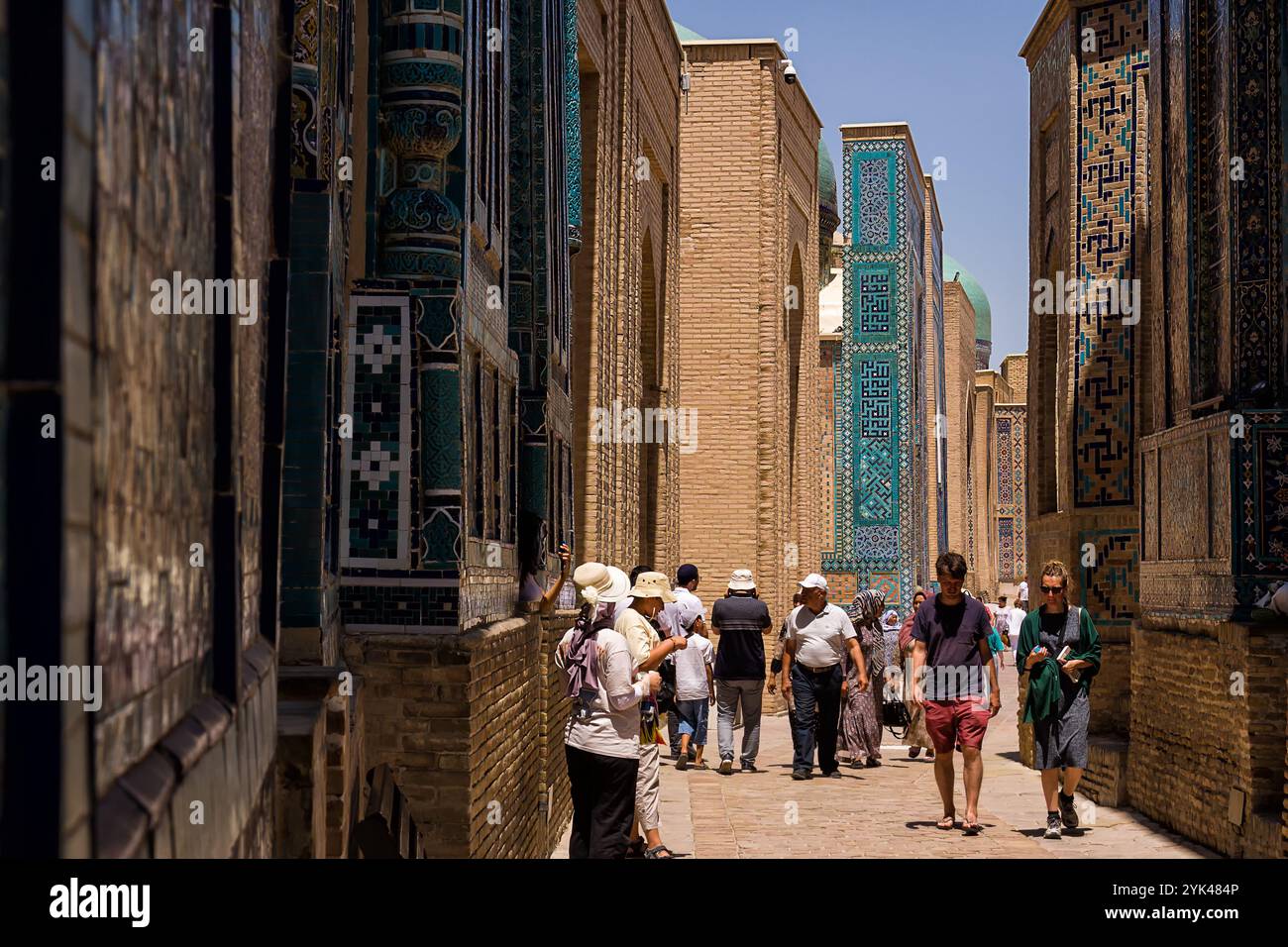 Samarkand, Usbekistan - 6. Juli 2024: Touristen und Pilger in der schmalen Straße von Shah-i-Zinda Mausoleen Stockfoto