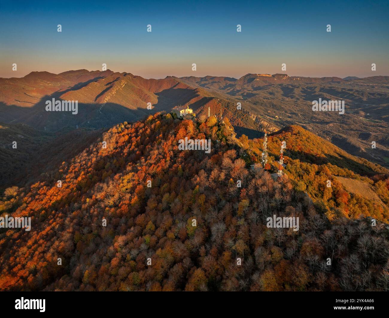 Blick aus der Vogelperspektive auf das Bellmunt Gebirge und das Heiligtum, bei einem Herbstuntergang mit den ockerfarbenen Buchenwäldern (Osona, ​​Catalonia, Spanien) Stockfoto