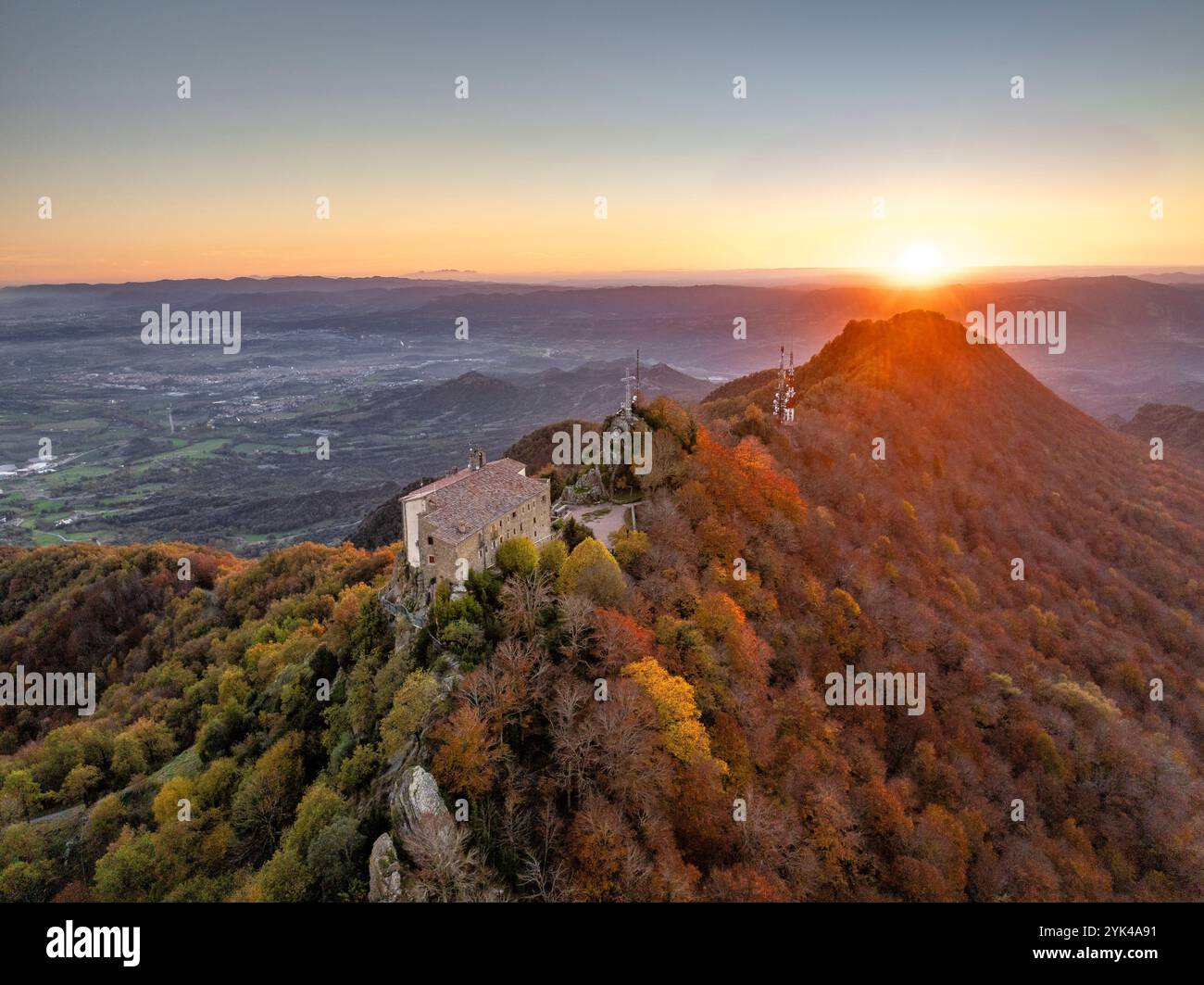 Blick aus der Vogelperspektive auf das Bellmunt Gebirge und das Heiligtum, bei einem Herbstuntergang mit den ockerfarbenen Buchenwäldern (Osona, ​​Catalonia, Spanien) Stockfoto