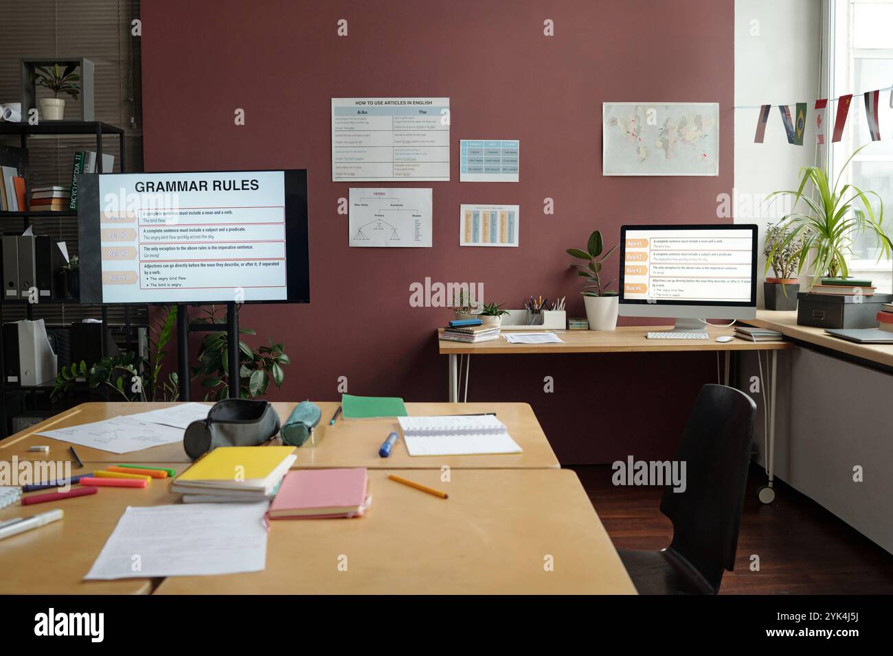 Interaktive Tafel mit Grammatikregeln, Plakaten an Wänden und breitem Tisch mit Copybooks, Stiften und Testpapieren im geräumigen Klassenzimmer Stockfoto