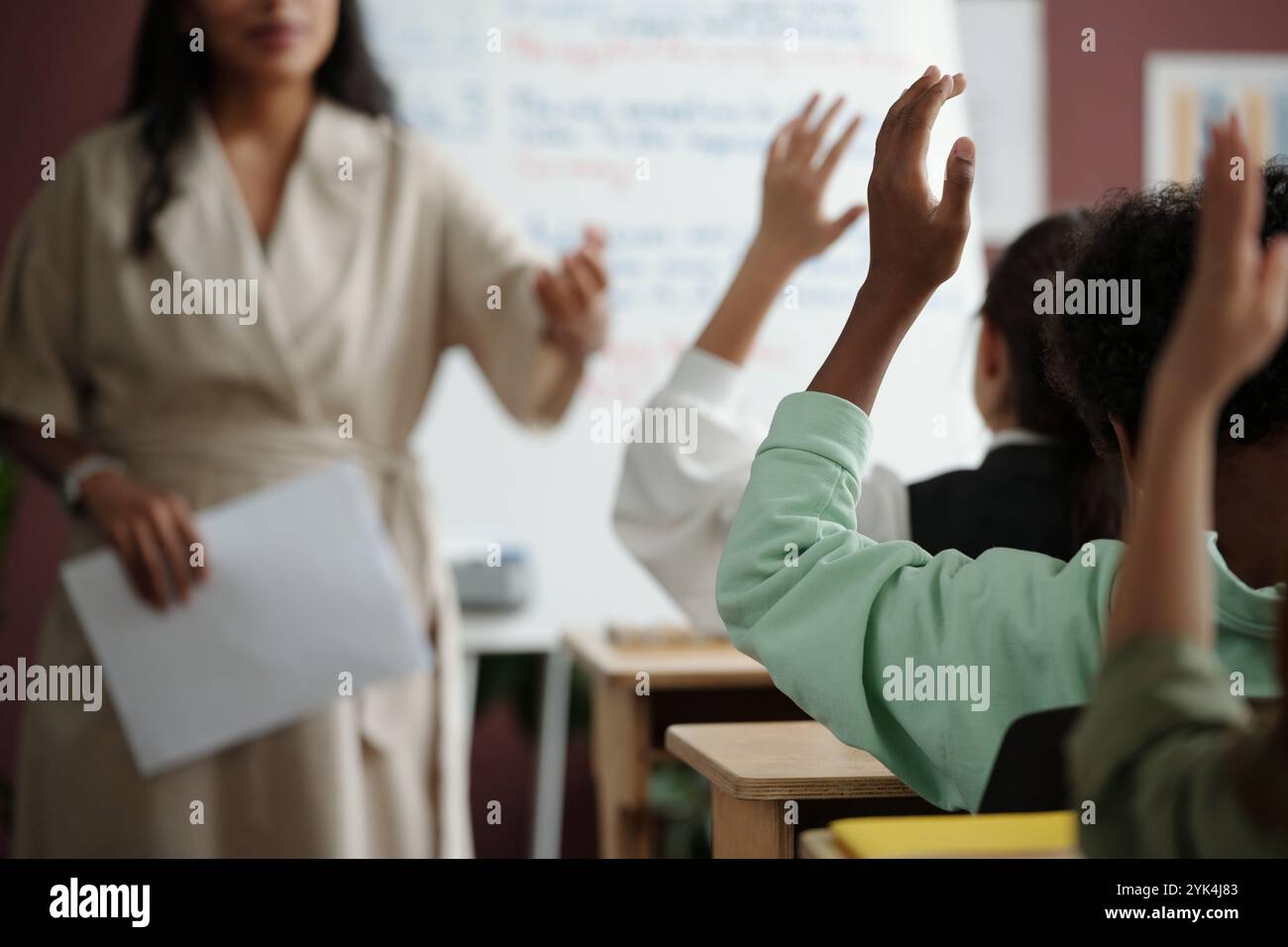 Konzentrieren Sie sich auf die Hand eines cleveren afroamerikanischen Schuljungen in lässiger Kleidung, der zwischen Klassenkameraden am Schreibtisch sitzt und im Unterricht arbeitet Stockfoto