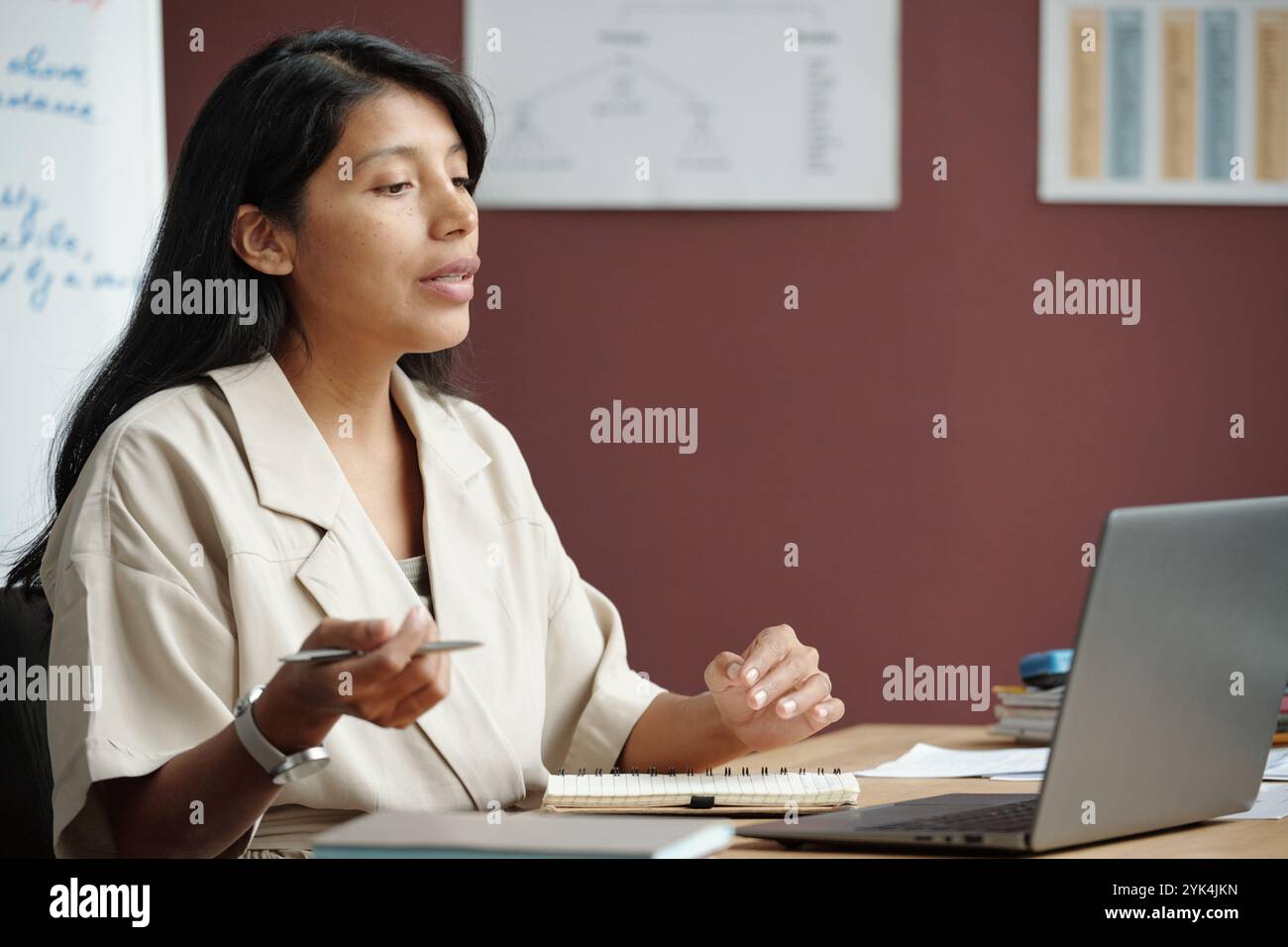 Junge Sprachlehrer, die Grammatikregeln vor Online-Publikum am Computer erklären, während sie am Arbeitsplatz sitzen Stockfoto