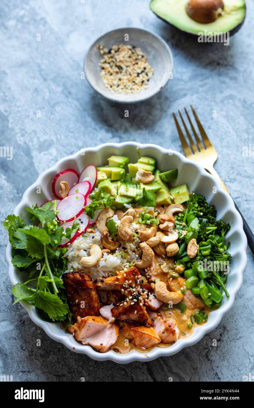 Reisschale mit Lachs, Avocado, Rettich, Brocoli und Currysauce Stockfoto