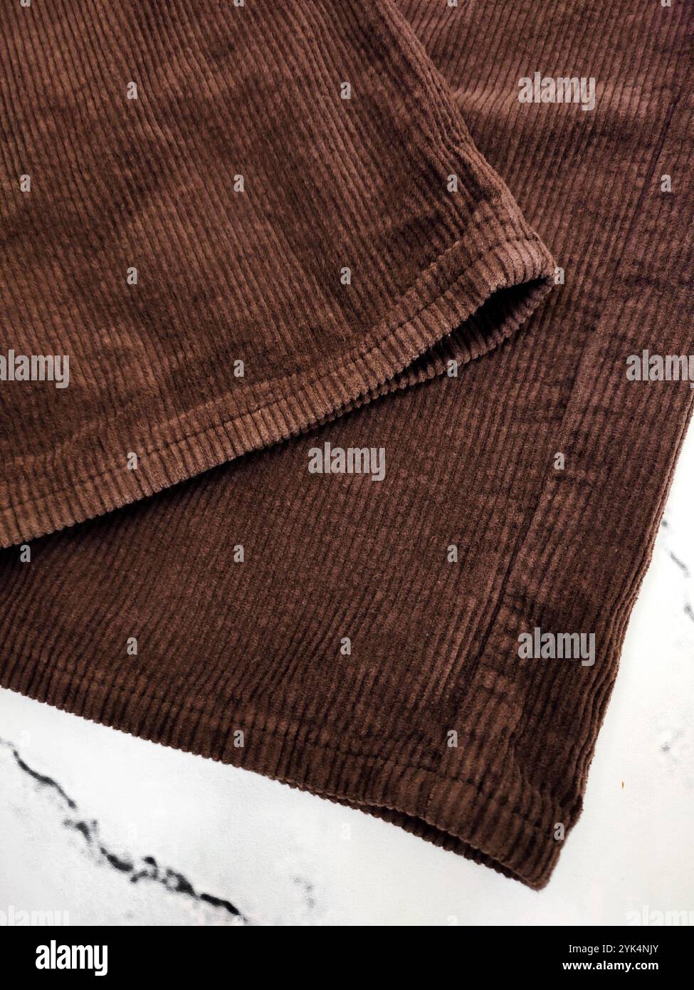 Braune Cordhosen Säume am weißen Marmorhintergrund von oben Ansicht, Kleidung, Stoff, Bekleidungsgeschäft, Nähen, Herstellung, Textil, Hosen Stockfoto