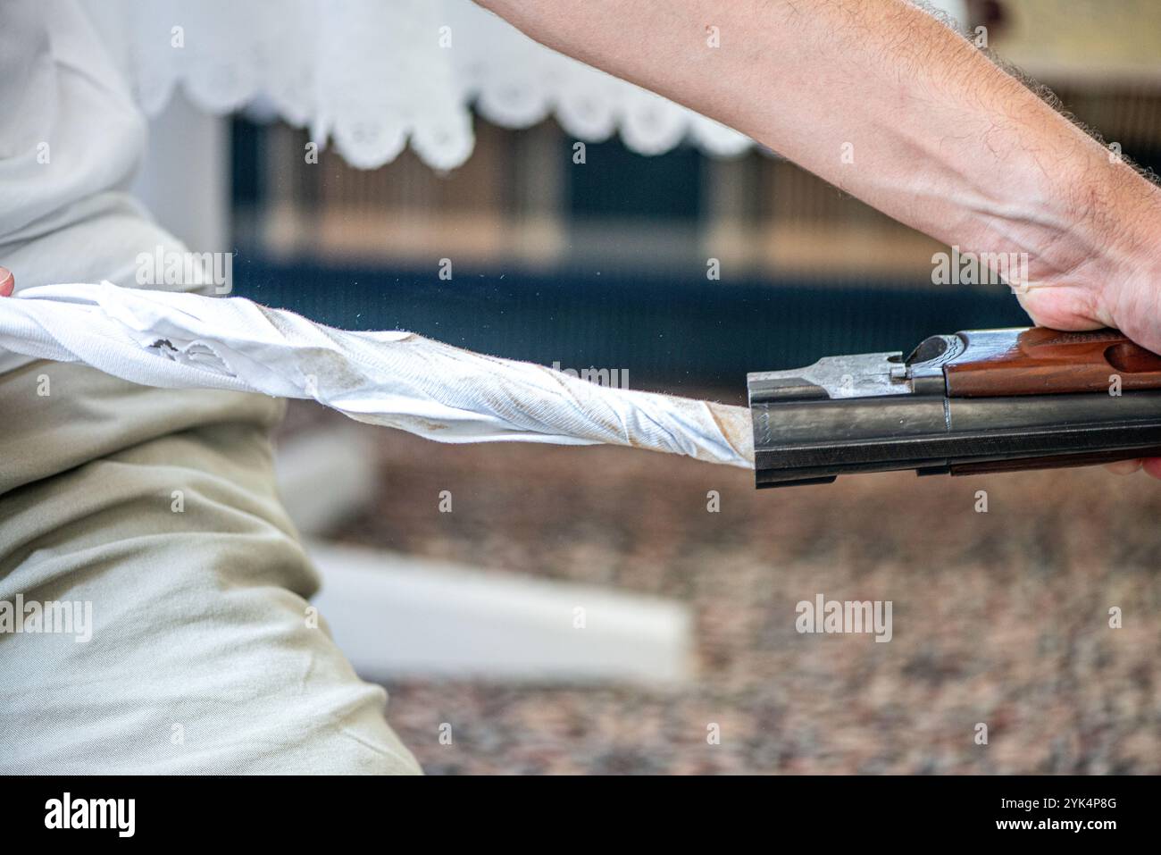 Ein Mann reinigt ein altes Gewehr sorgfältig mit Öl und Reinigungsgeräten und zeigt die Liebe zum Detail und die Handwerkskunst alter Schusswaffen. Stockfoto