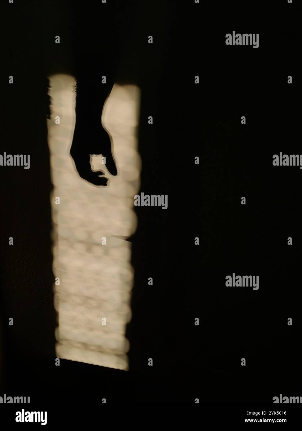 Hängende Geste: Von Hand beleuchtet durch Sonnenlicht im dunklen Negativraum Stockfoto