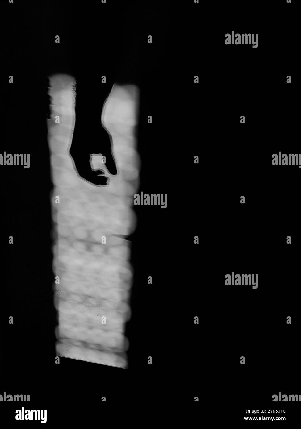 Hängende Geste: Von Hand beleuchtet durch Sonnenlicht im dunklen Negativraum Stockfoto