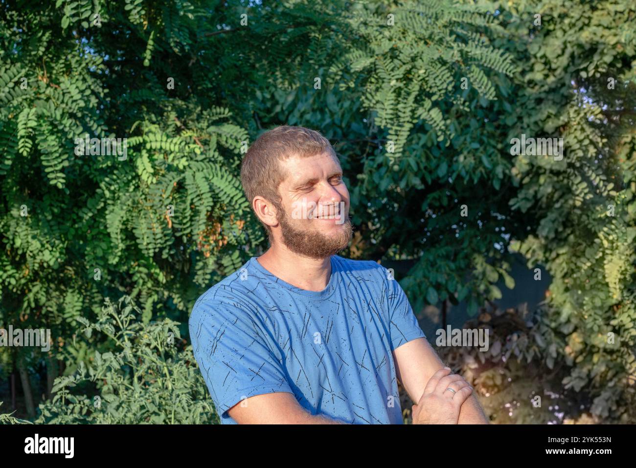 Glücklicher kaukasischer Mann mit Bart, der im grünen Park lächelt. Stockfoto