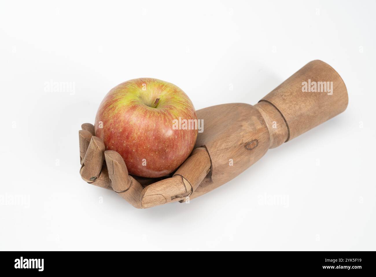 Ein Apfel in der Handfläche einer hölzernen Hand auf weißem Hintergrund Stockfoto