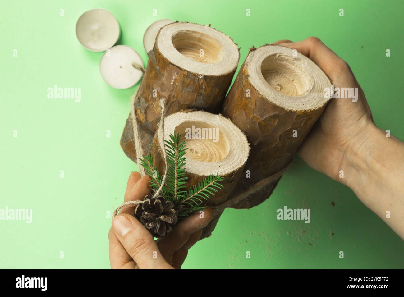 Kerzenhalter für Heimwerkerweihnachten aus Pinienstämmen, Kerzen, handgefertigten Seilen, Tannenzweigen und Tannenzapfen. Die Dekoration wird mit den Händen befestigt. Schritt-für-Schritt-Anleitung Stockfoto