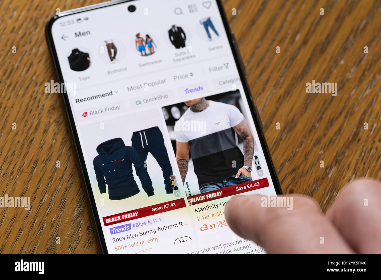 Man Browsing Black Friday bietet Herrenbekleidung in der Shein App auf einem Smartphone, Großbritannien. Shein ist ein weltweit tätiger Online-Händler für Mode und Lifestyle Stockfoto