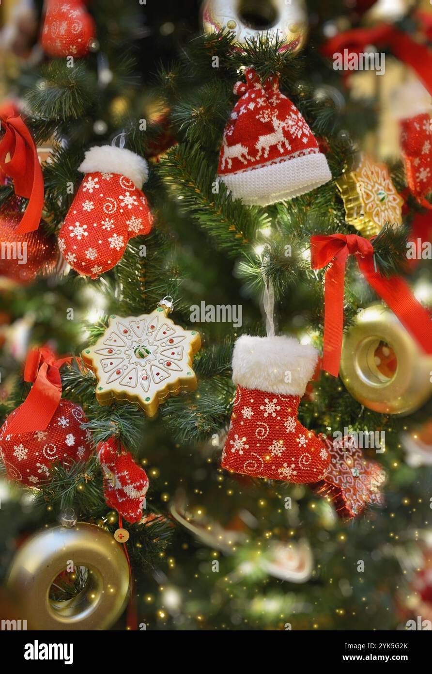 Weihnachtsbaum mit vielen roten Ornamenten. Gestrickte Spielzeugdekorationen. Weihnachtliche Einrichtung. Winterferienthema. Silvesterfeiern. Stockfoto