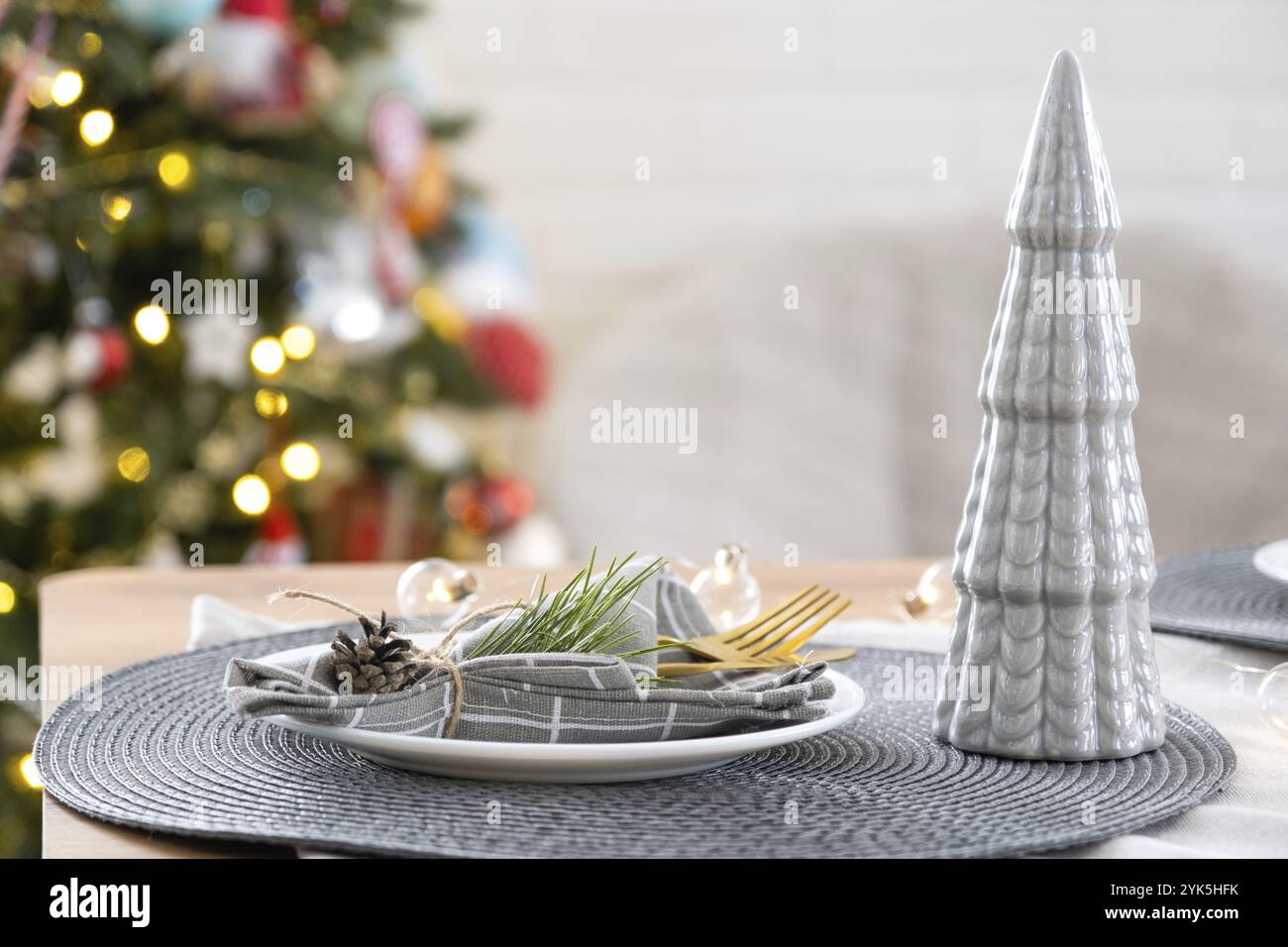 Ein festlicher Tisch mit Tellern, Gabeln, Messern, Servietten in einem Käfig, der für Weihnachten und Neujahr mit einem Kegel dekoriert ist. Eg Stockfoto