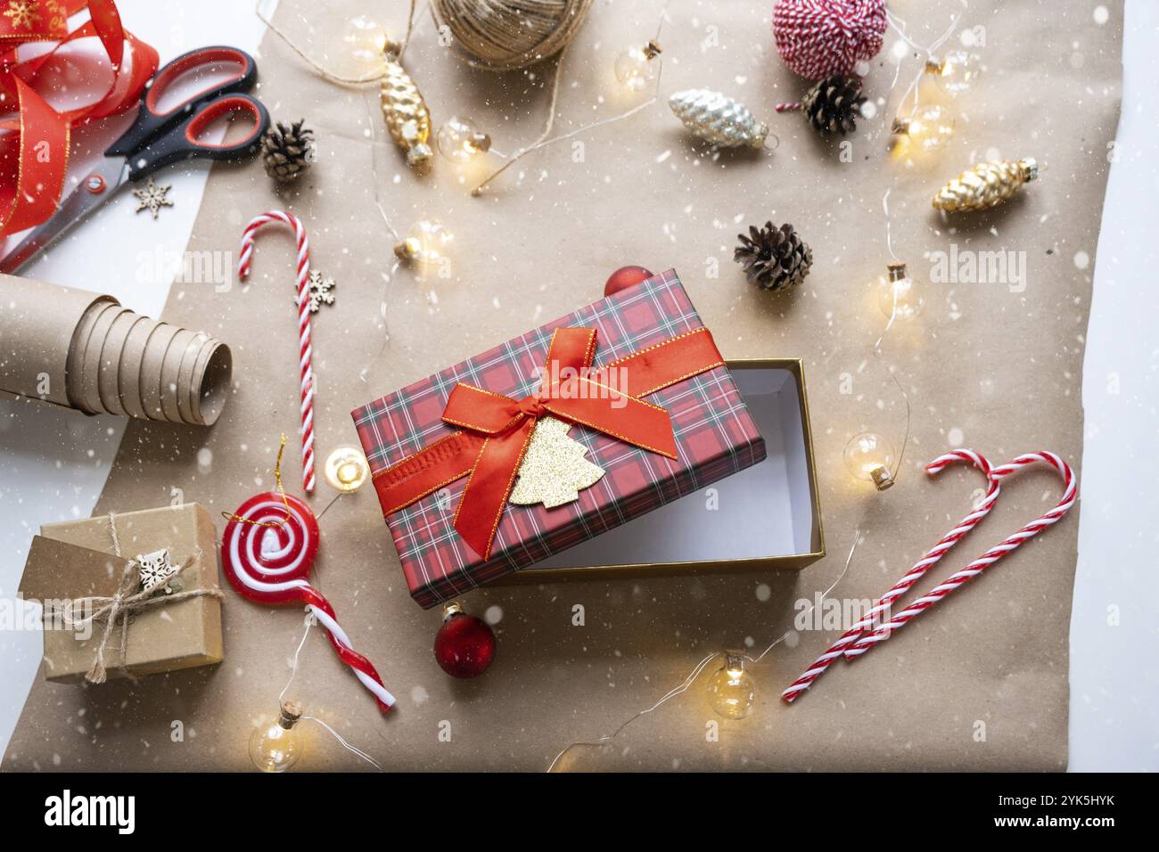 Packen Sie ein Geschenk für Weihnachten und Neujahr in Kraftpapier, Kegel, Klebeband, Schere. Tags mit Mock-up, natürliches Dekor, handgemacht, DIY. Festliche Stimmung. Flach Stockfoto