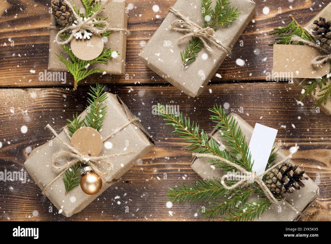 Packen Sie ein Geschenk für Weihnachten und Neujahr in umweltfreundlichen Materialien: kraftpapier, Tannenäste, Zapfen, Garn, Schnee. Anhänger mit Modell, natürliche Einrichtung Stockfoto
